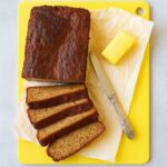 Sliced high-protein banana bread made with cottage cheese, served with butter on parchment paper