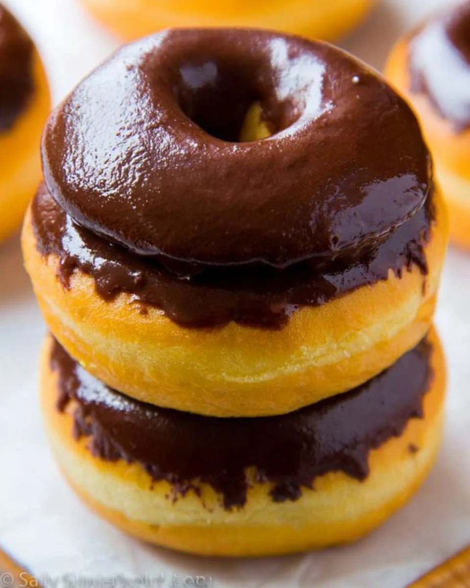 Delicious chocolate frosted donuts displayed on a wooden table.