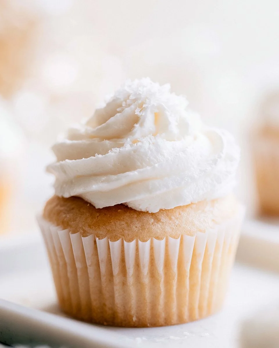 Healthy vanilla cupcakes topped with icing and sprinkles on a plate